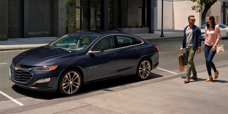 A 2025 Chevrolet Malibu parked in front of a building, showcasing its sleek design and modern features.